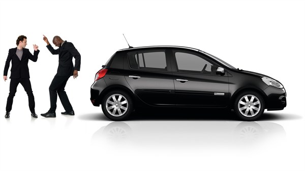 Two men dressed up in suits are dancing behind a Renault CLIO
